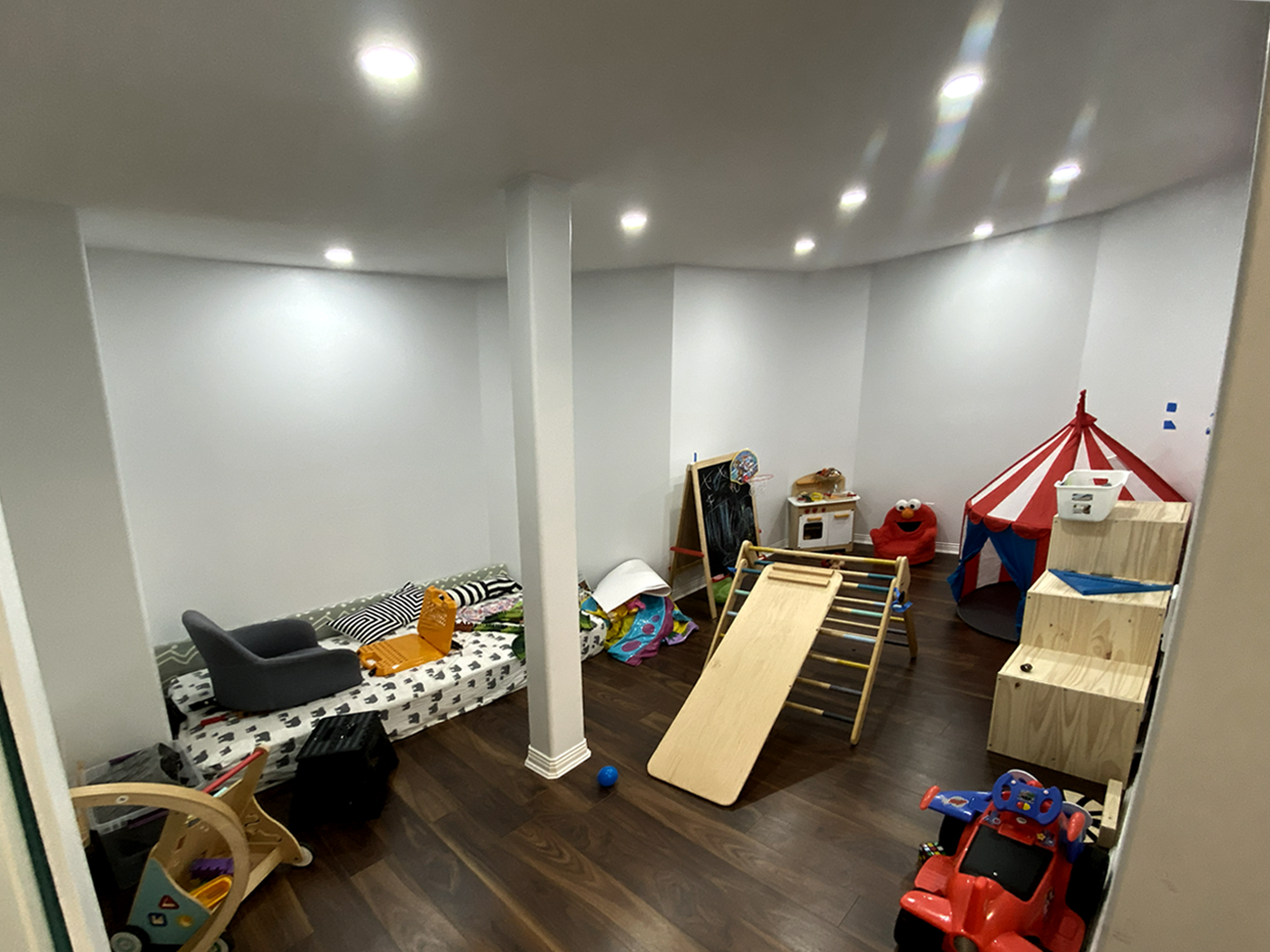 Unorganized kids’ playroom with Pikler triangle, toy kitchen, and scattered play items — no defined layout or functional design.